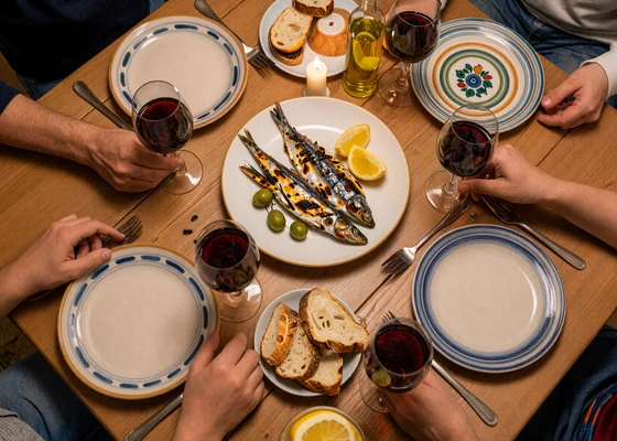 Traditional Portuguese family dinner with grilled sardines, bread, and wine on a rustic table