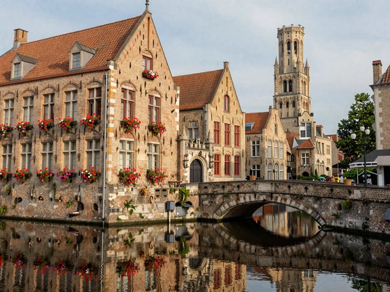 Picturesque medieval street in Bruges Belgium with canal reflections and flower-decorated buildings