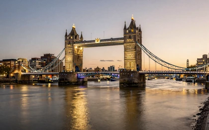 London Tower Bridge illuminated at twilight reflecting on Thames River