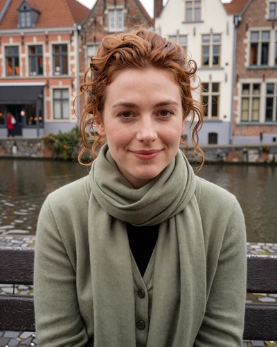 Charlotte, 27, Belgian woman with auburn curly hair sitting by a canal in Ghent